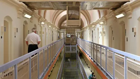 Corbis via Getty Images A prison officer walks down a wing of a prison.