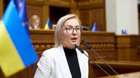 Inna Sovsun Inna Sovsun speaks in Parliament in Kyiv with Ukrainian flag behind.