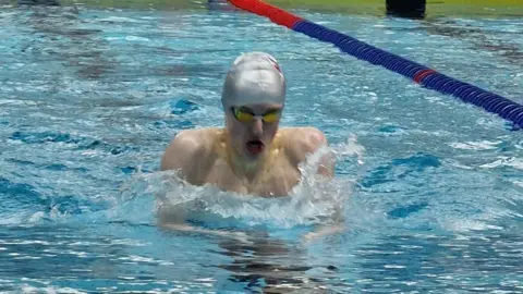 Dave Carrington A teenage boy in goggles and a swimming cap in a pool.