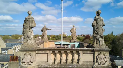 Four weather beaten statues stand over the skyline