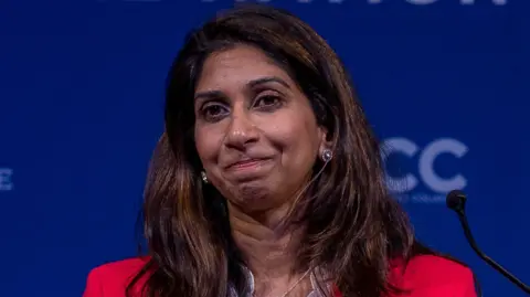 Suella Braverman, who is wearing a red suit jacket