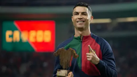 Cristiano Ronaldo holds an award ahead of making his 200th appearance for Portugal last year.