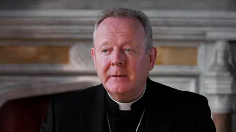 Archbishop Eamon Martin, with short grey hair, dressed in black and pictured from the shoulders up. 