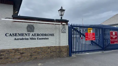 A blue gate and a wall with a sign reading "casement aerodrome". 