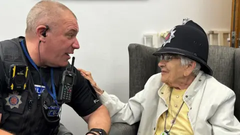 Essex Police Police officer Neil Brand with Gwen Lewis wearing a police helmet