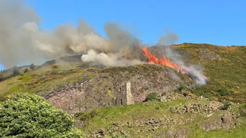 there are flames and smoke as the hillside fire burns