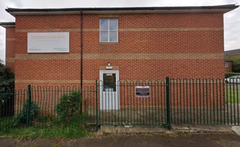 Google Brick side wall of care home with one door and sign visible
