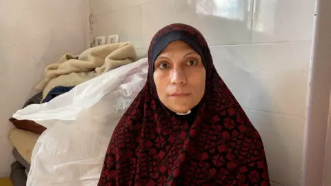 Lina Ibrahim Abu Namos  wears a red and black patterned hijab and was interviewed by the BBC in a hospital in Gaza.