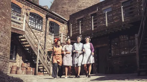 A group of women stand in front of a pottery factory.