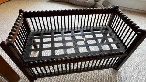 The old wooden cot Mrs Mathers has kept.