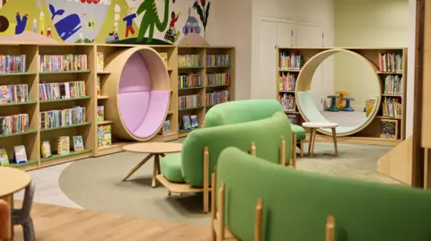 Stockport Council A children's learning area with colourful furniture, book-lined walls and murals on the walls