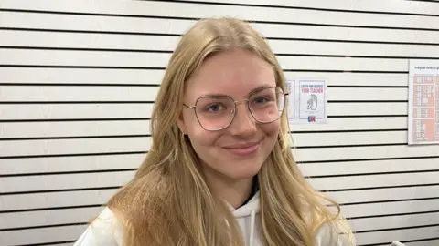 A head and shoulders picture of Vlada Zabielina, a Ukrainian refugee now living in Southend. She has long blonde hair and is wearing glasses.