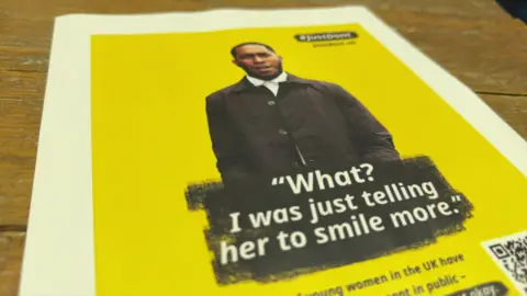 Close up shot of a campaign poster with a yellow background. It feature an image of a young man and the slogan: "What? I was just telling her to smile more."