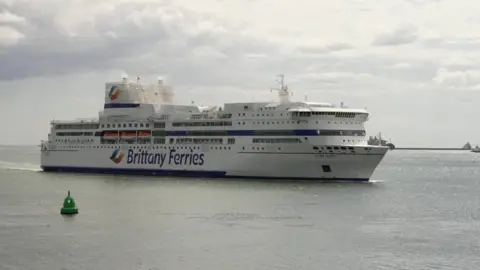 A Brittany Ferries ferry passing a green buoy at sea.