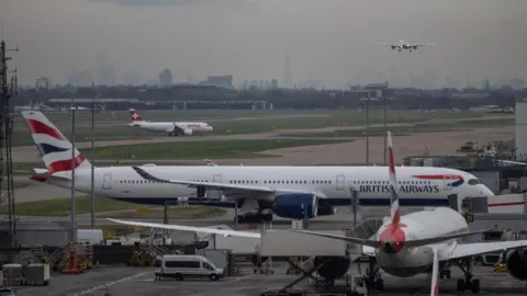 Reuters Three planes sit on the tarmac of an airport while another plane approaches the runway.