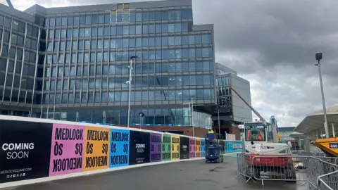 Phototgraph of Medlock Square under construction at the Etihad Stadium. The image shows construction boards behind the North Stand.