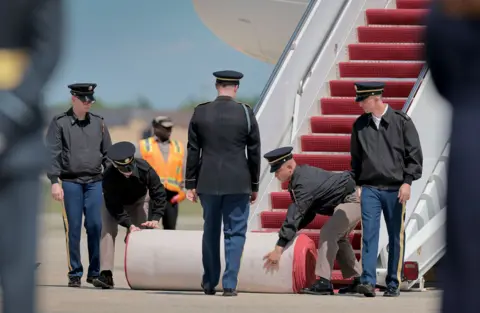 Getty Images Members of the U.S. military roll out a red carpet at the foot of the stairs to the plane carrying King Charles III and Queen Camila on day one of their State Visit to the United States, on April 27, 2026 at Joint Base Andrews, Maryland.