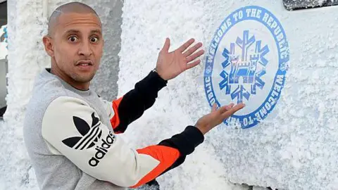 Getty Images  DJ Warras wearing a sweater written adidas while standing next to a lorry covered in snow 