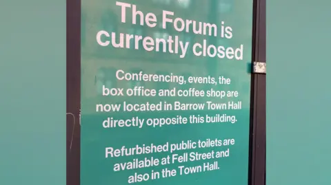 Posters on The Forum's windows saying the Barrow venue is closed and directing people to other venues for services.