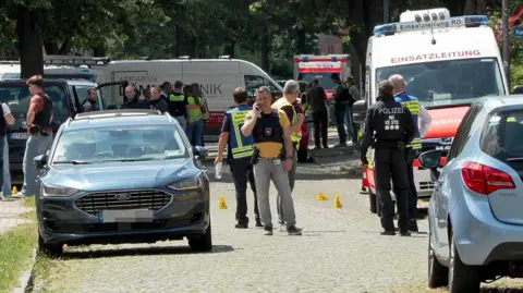 AFP via Getty Images Crowds of emergency workers stand in the road following a shooting in Stade, northern Germany. 
