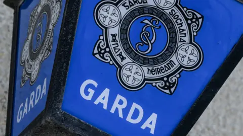 Generic picture of a Garda sign, close up of the force badge in celtic style, white text on blue background 'Garda'