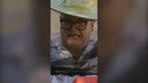 Alan wears beekeeping garb