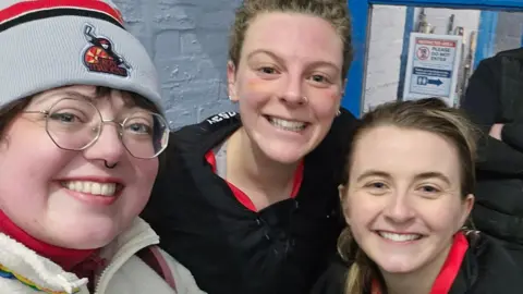 Georgia Grainger Three women wrapped up warm smiling at the camera.