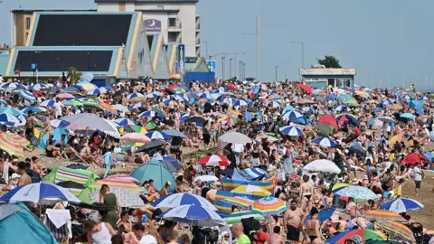 A crowded beach of umbrellas and people in bathing suits in Southend
