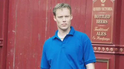 A shot of Ricky Groves from 2000 standing outside the Queen Vic pub on the set of EastEnders.