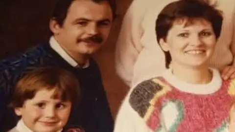 Family handout An old family posed photograph featuring a small boy about six, a woman in a cream, pink, yellow, green and brown jumper with short brown hair and a man in a dark jumper with dark hair and moustache.