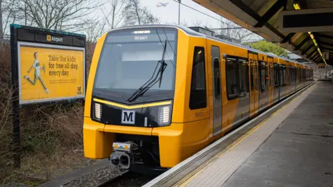 One of the new Tyne and Wear Metro trains, which is yellow and grey, at Airport.