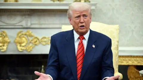 Getty Images President Trump uses a blue suit and a red tie while gesture while sitting in a chair in the Oval Office of the White House