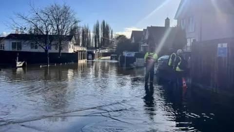 BCP Council People in hi-vis vests wade through the flooded residential area.