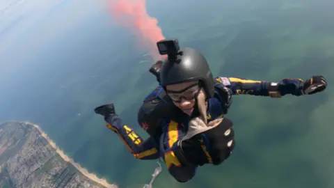 Tigers Army Parachute Display Team A member of the Tigers Army Parachute Display Team gives a thumbs up to the camera mid-air