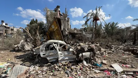 Getty Images A damaged car in the middle of rubble in Gaza