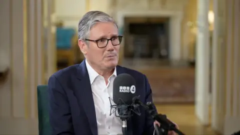Keir Starmer sitting at table talking into microphone during interview