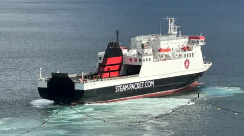 The Ben-my-Chree, which features the white, red and black colours of the Isle of Man Steam Packet Company along with it's logo on the side. The vessel also features the firms website address of STEAM-PACKET.COM in white lettering on the side.