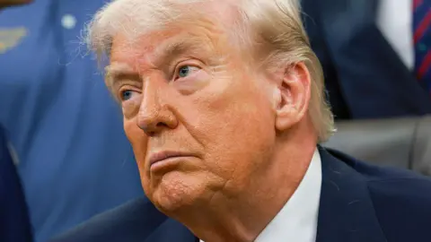 Trump listening to a conversation while wearing a suit
