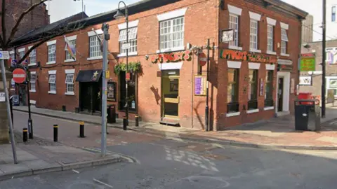 A street corner with a takeaway in a brick building, which has a red sign reading McTucky's Fried Chicken