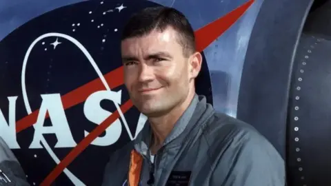 La NASA Fred Haise sonríe mientras se para frente a un avión de entrenamiento de la NASA