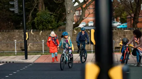 Getty Images A group of people cycling and walking at a pedestrian crossing.