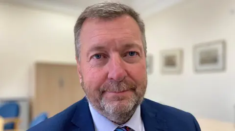 Reform UK Councillor Sean Matthews, A middle-aged bearded white man in a blue suit