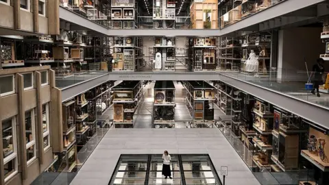 A visitor looks at the artefacts exhibited in the main room of the newly opened museum V&A East Storehouse, in east London.