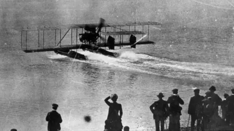 Ian Gledhill A seaplane lands on the sea in Brighton with crowds watching in the early years of the 20th Century