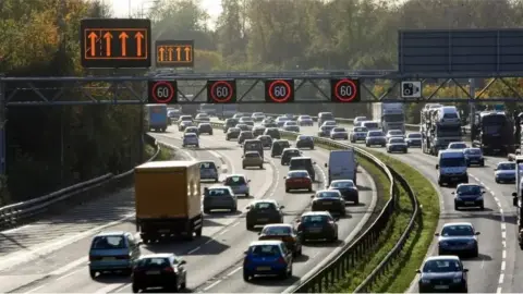 PA A photo of a smart motorway. Electronic displays are attached to a grid above the road, detailing to drivers any changes to each of the lanes. For example, in this case, each lane has been given a 60mph speed limit.