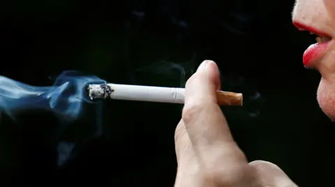 Close up of a woman holding a lit cigarette in her hand