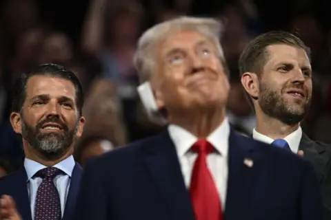 Getty US former President and 2024 Republican presidential candidate Donald Trump looks on as his sons Donald Trump Jr. (L) and Eric Trump stand behind him during the first day of the 2024 Republican National Convention 