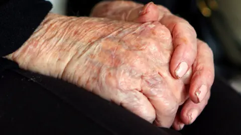 A elderly person's hands clasped together.