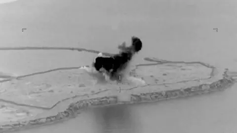 A black and white image of smoke rising from a foreshore. 