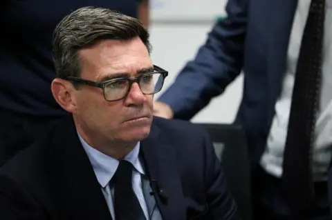 Burnham sitting down, wearing a blue suit